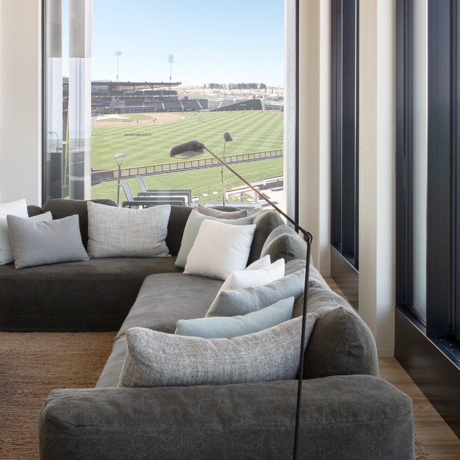 a room with a couch and a view of a baseball field