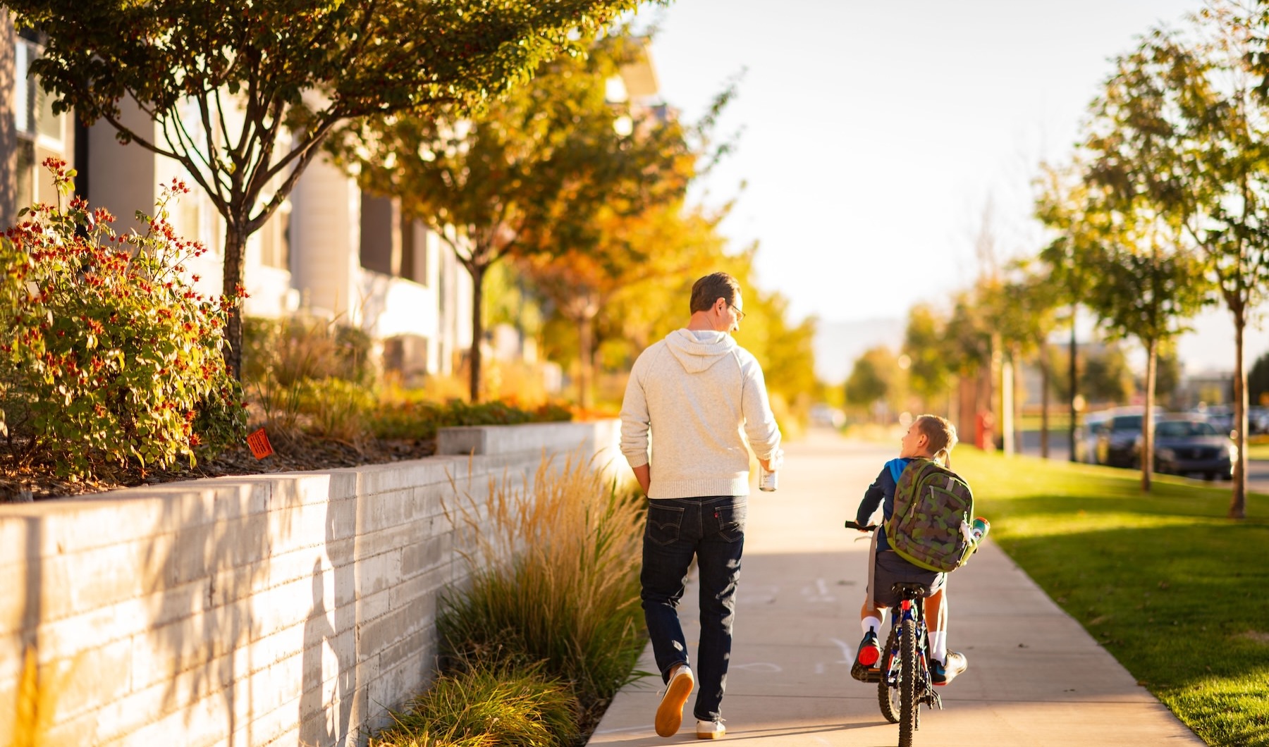 a father and son on a bike going down a sidewalk